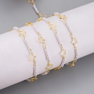 Detail of gold chain necklace featuring white pearls and polished hollow star pendants
