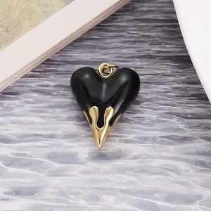 Detail view of a black heart pendant with golden lava drip metal design and top ring