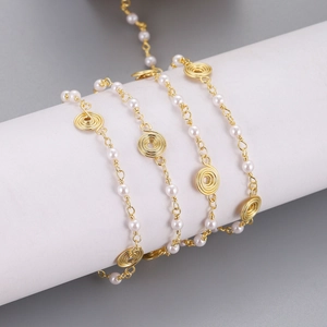 Detail of light gold necklace chain with white pearls and spiral metal wire discs