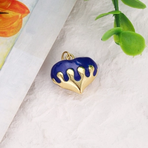 Macro detail of heart charm with blue enamel drip on gold-plated copper pendant
