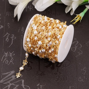 Roll of DIY jewelry chain with gold butterfly charms and white faux pearls on spool