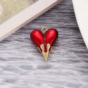 Detailed view of red heart pendant with gold flame setting on water ripple paper background