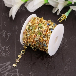 Detailed macro view of gold hollow chain spool with multicolor gemstone inlay for DIY jewelry