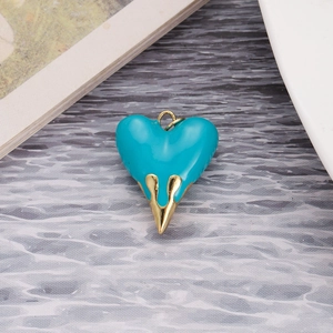Macro detail of blue enamel lava heart pendant with gold metal spike and ring