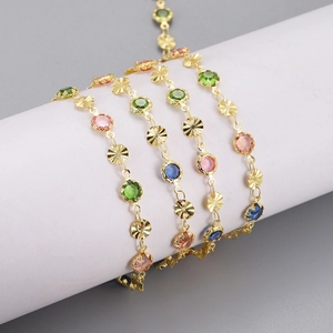 Detailed close-up of gold chain featuring multi-colored crystals and textured floral metal links