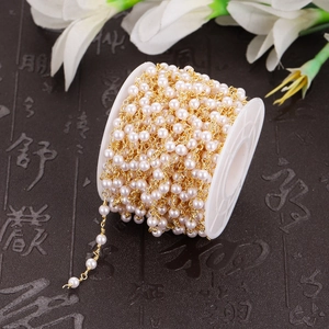 Detail of white pearls with gold metal chain on a white spool for DIY jewelry making