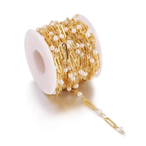 Gold paperclip chain with white pearls for DIY jewelry making on a white plastic spool