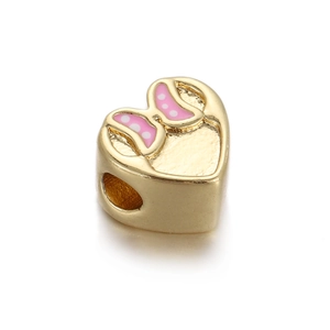 Macro shot of gold-plated heart-shaped bead with pink polka dot bow for DIY jewelry making