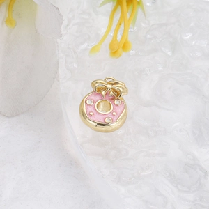 Macro view of a pink donut pendant with a golden bow and enamel finish for DIY jewelry