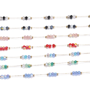 Detailed macro view of colorful faceted crystal beads on a thin gold stainless steel chain