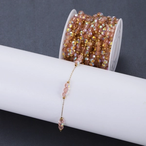 Pink AB crystal bead chain with golden stainless steel links on a display roll