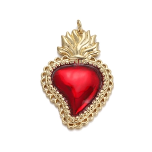 Macro detail of sacred heart pendant with red crystal inlay and gold-plated flame design