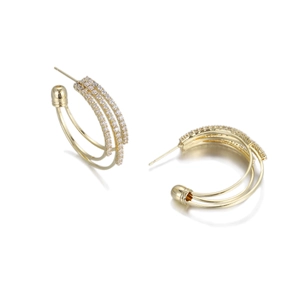 Macro detail of golden triple-hoop earrings featuring pavé crystals and polished texture