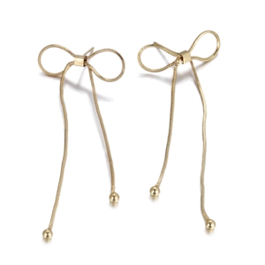 Detail of golden bow-knot earrings with long snake chain tassels and metallic sphere drops