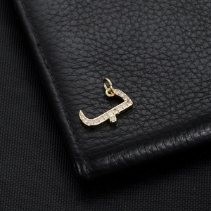 Macro shot of 14K gold plated Arabic letter pendant with pavé cubic zirconia