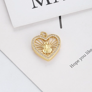 Macro detail of a 14K gold plated heart pendant featuring a religious icon and crystals