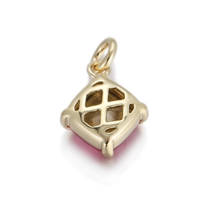 Macro detail of geometric copper pendant with gold finish and pink gemstone inlay