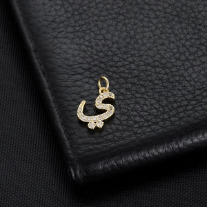 Macro detail of Arabic letter pendant with gold plating and cubic zirconia inlay