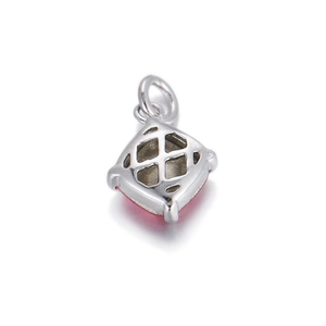 Macro detail of silver pendant with red stone and diamond-shaped cutout back design