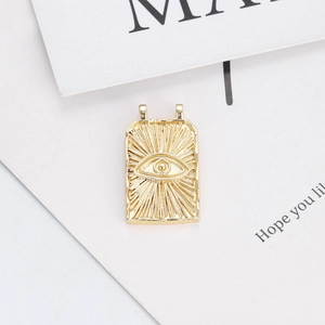 Detailed macro of a rectangular 14K gold plated Evil Eye pendant with ray texture