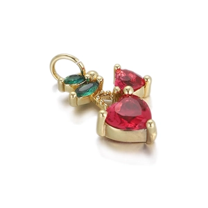 Macro view of a 14K gold plated cherry pendant with red heart crystals and green leaves