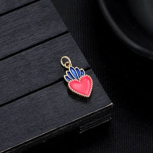 Macro detail of red heart-shaped enamel jewelry charm with gold metal edges and blue accent