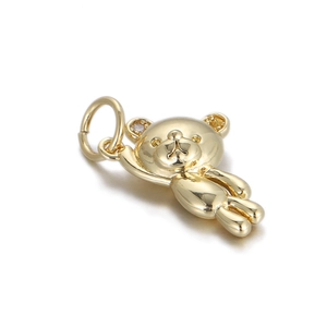 Macro detail of polished gold-plated bear pendant with a tiny sparkling zircon stone