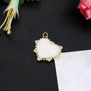Detailed close-up of a heart-shaped gold enamel pendant with small rhinestones