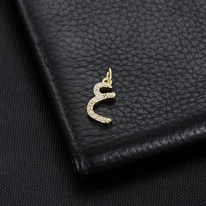 Detail shot of a 14K gold-plated Arabic letter pendant with inlaid white zircon stones