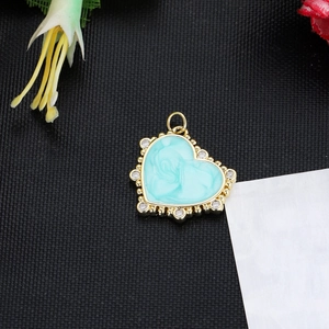 Macro detail of a 14K gold-plated heart pendant with blue marble texture and zircon stones