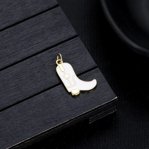 Detail of white enamel cowboy boot pendant with gold star on dark wood background
