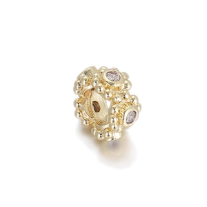 Detail of gold beaded charm with sparkling cubic zirconia stones and vintage texture