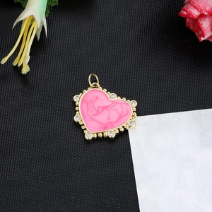 Detailed macro view of heart charm pendant with pink enamel and sparkling zircons