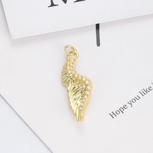 Macro view of gold-plated wing charm with small white pearl inlay for DIY jewelry
