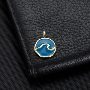 Macro shot of 14K gold plated marine wave pendant with blue enamel on black leather background