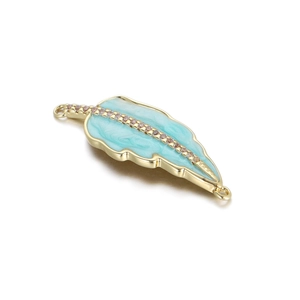 Macro detail of a 14K gold plated feather connector with blue marble enamel and zircon inlay