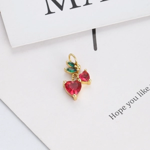 Macro shot of 14K gold plated cherry pendant with red heart crystals and green leaves