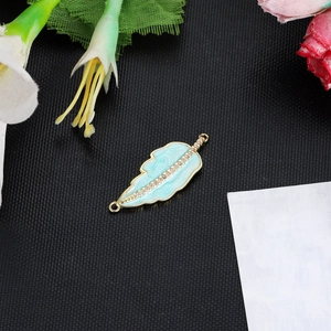 Detailed macro view of a light blue enamel feather connector with zircons for jewelry DIY