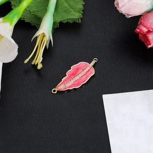 Macro detail of red enamel leaf charm with sparkling crystals and gold finish