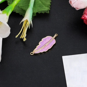 Detail of a 14K gold plated pink enamel feather charm with sparkling rhinestones for jewelry DIY