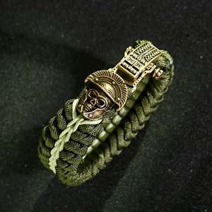 Macro detail of bronze samurai skull buckle on olive green braided survival paracord bracelet