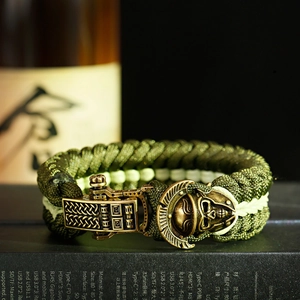 Macro detail of paracord bracelet showing bronze skull buckle and green woven texture
