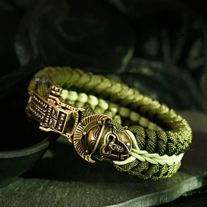 Detail of army green paracord survival bracelet with a bronze Spartan skull clasp