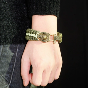 Close-up of army green paracord survival bracelet with bronze skull and mechanical clasp