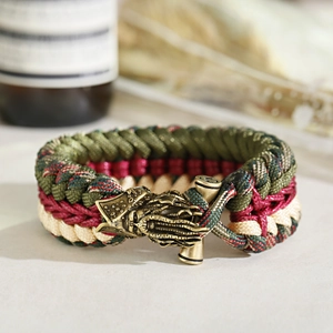 Macro shot of green and red woven paracord bracelet with antique bronze dragon clasp