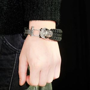 Close-up of men's paracord survival bracelet with detailed silver spartan helmet buckle