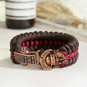 Detail of paracord survival bracelet with bronze skull helmet buckle on rustic background