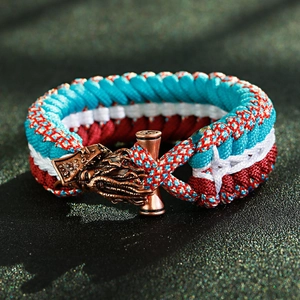 Macro detail of bronze dragon head clasp on multi-color paracord braided survival bracelet