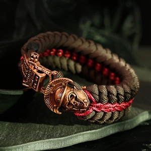 Detail of paracord survival bracelet with a bronze skull helmet charm and metal buckle