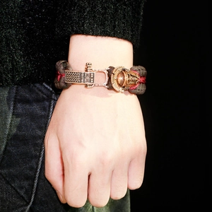 Detail of paracord survival bracelet featuring bronze skull mask and patterned metal buckle